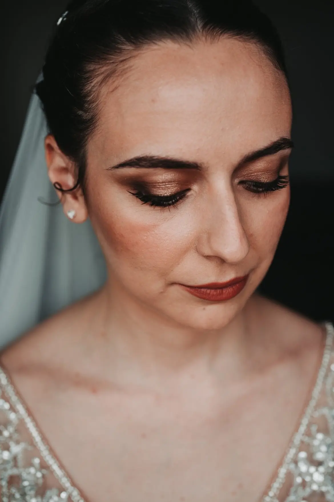 A refined bridal look with bronze and copper eyeshadows, voluminous lashes, and terracotta lips for a sophisticated, timeless beauty.
