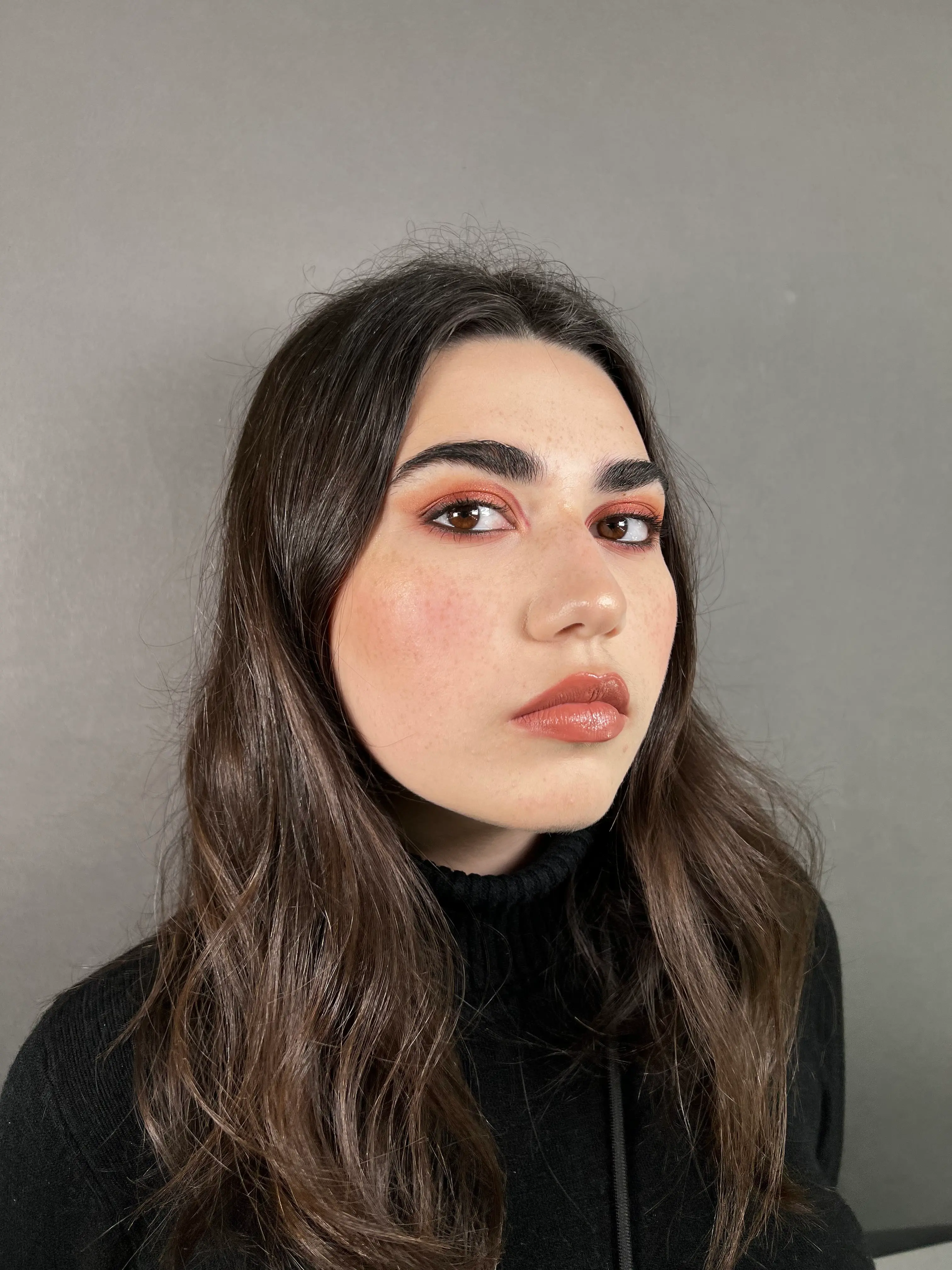 Warm orange tones on the eyes paired with glossy nude lips for an elegant, natural look.